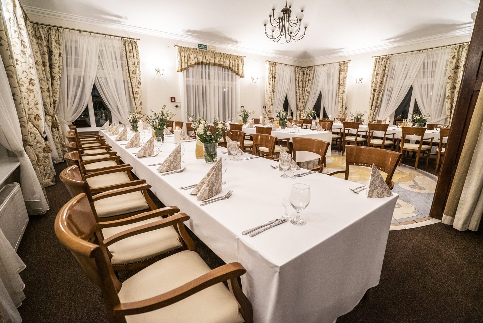 Kardamon banquet hall — long tables, chandelier, cream drapery